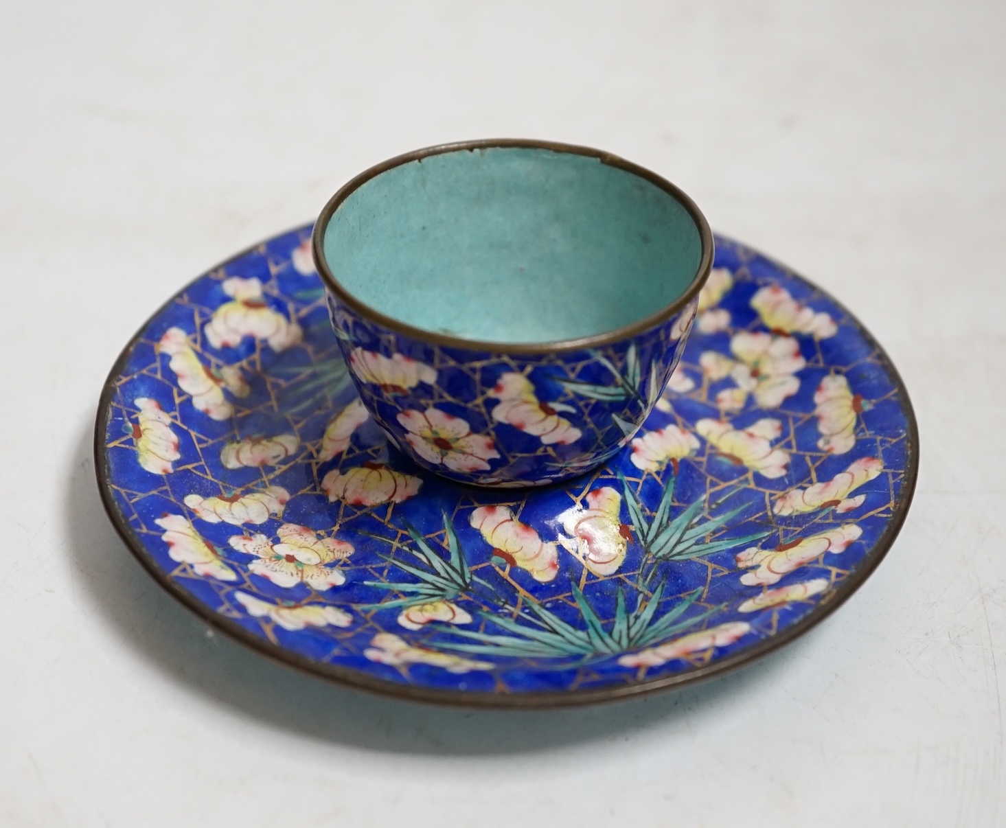 A 19th century Canton enamel tea bowl and stand, 11cm in diameter. Condition - saucer good, cup poor
